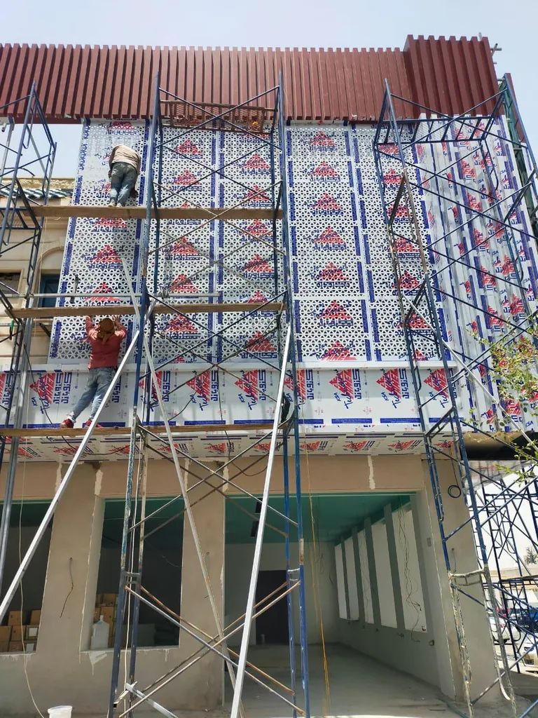 ترميم واجهة مبنى مع سقالات وسقف معدني
